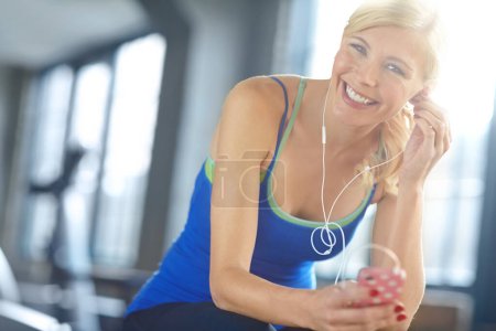 Photo for Finding the perfect workout track. Portrait of a beautiful young woman listening to music during her workout at the gym - Royalty Free Image