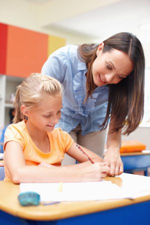Photo for Youre on the right track. A beautiful young teacher helping a student with her schoolwork - Royalty Free Image
