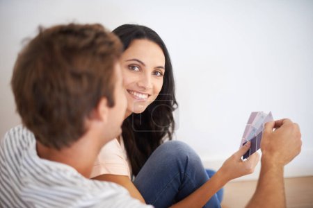 Téléchargez les photos : Quelle couleur aimez-vous ? Un jeune couple dans sa nouvelle maison regardant des échantillons de couleur - en image libre de droit