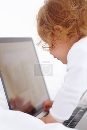 Foto de ¿Qué es esta madre? Una niña jugando con su computadora portátil de mamás - Imagen libre de derechos