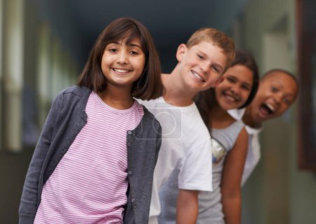 Foto de Alineados para clase. Retrato de una joven feliz de pie en un pasillo con sus amigos detrás de ella - Imagen libre de derechos