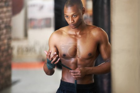 Foto de Recogiendo sus pensamientos y empapando su mente. Un boxeador afroamericano atando sus manos en el gimnasio - Imagen libre de derechos