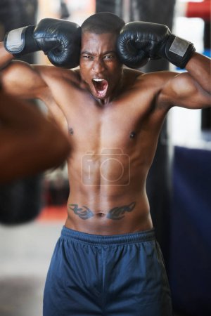 Foto de Cada fibra de su cuerpo quiere luchar. Un boxeador afroamericano con los puños contra la cabeza levantándose para pelear - Imagen libre de derechos