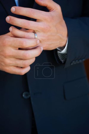 Téléchargez les photos : Fiers de sa nouvelle parure. Gros plan d'un marié ajustant nerveusement la bague sur son doigt - en image libre de droit