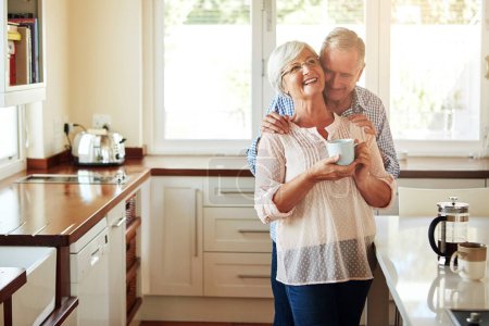 Photo for Making a point of showing that he missed her. an affectionate senior couple in the kitchen - Royalty Free Image