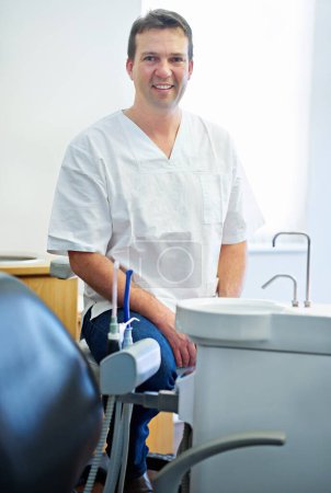Foto de Tu amigable dentista. Retrato de un dentista sentado junto al equipo dental en su consultorio - Imagen libre de derechos