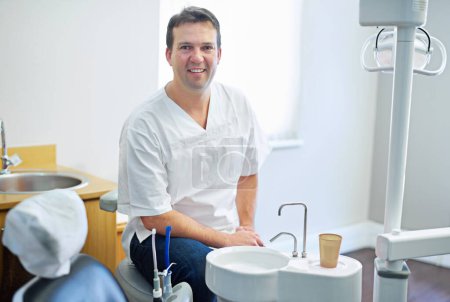 Foto de Prometo que no dolerá ni un poco. Retrato de un dentista sentado junto al equipo dental en su consultorio - Imagen libre de derechos