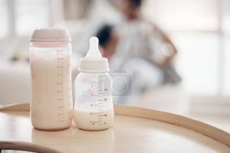 Téléchargez les photos : La bonne formule peut aider au développement de vos bébés. Plan déconcentré d'une jeune mère biberon nourrissant sa fille sur le canapé - en image libre de droit