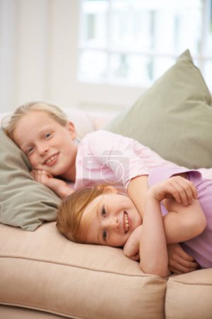 Photo for These sisters are the best of friends. Portrait of two young sisters lying on the sofa at home - Royalty Free Image