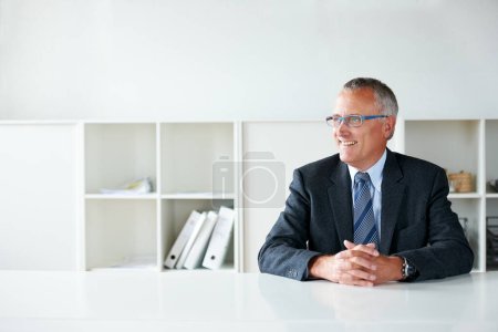 Téléchargez les photos : Heureux de ce qu'il a accompli. un homme d'affaires senior assis à une table - en image libre de droit