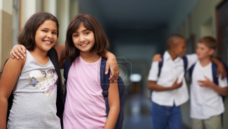 Foto de De vuelta a la escuela. Dos niñas de la escuela de pie con sus brazos alrededor de los hombros del otro en el pasillo - Imagen libre de derechos