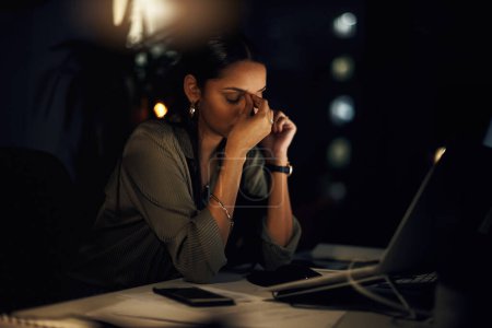 Photo for Im too tired to deal with these deadlines. a young businesswoman looking stressed out while working in an office at night - Royalty Free Image