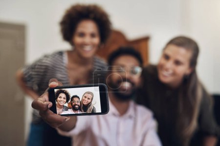 Foto de Vamos a tomar algunos selfies para nuestro perfil de negocio. un grupo de empresarios tomando selfies juntos en una oficina - Imagen libre de derechos