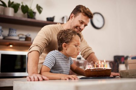 Foto de Tienes que atraparlos a todos. un chico soplando las velas en su pastel de cumpleaños mientras celebraba con su padre - Imagen libre de derechos