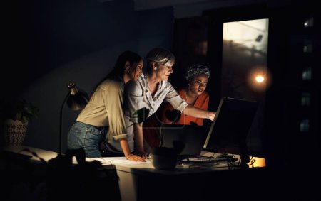 Photo for Anything we can do about this. a group of businesswomen working together on a computer in an office at night - Royalty Free Image