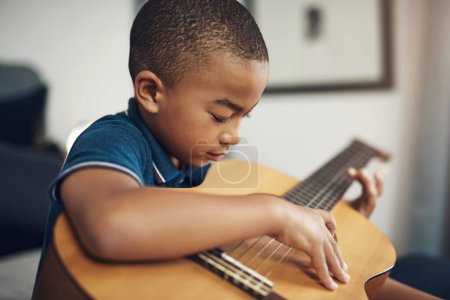 Foto de He tenido algunas lecciones. un joven tocando la guitarra en casa - Imagen libre de derechos