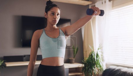 Photo for Im going to have some serious guns this week. a young woman working out using weights at home - Royalty Free Image