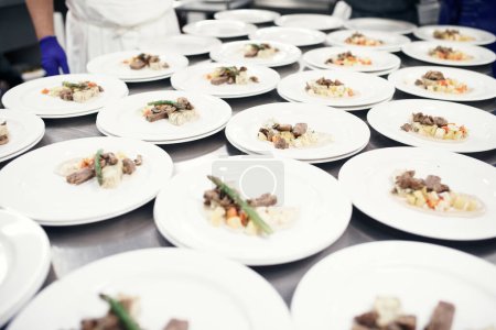 Photo for Prepped and ready for the waiters. plates being prepared for a meal service in a professional kitchen - Royalty Free Image