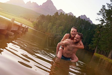 Téléchargez les photos : Rire sous le coucher du soleil. un jeune couple affectueux profitant d'une baignade ensemble dans un lac - en image libre de droit