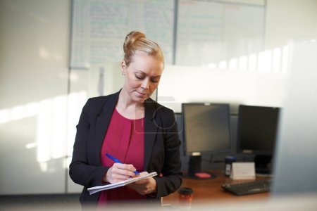 Foto de Tomando algunas notas en la oficina. una atractiva mujer de negocios haciendo notas en la oficina - Imagen libre de derechos