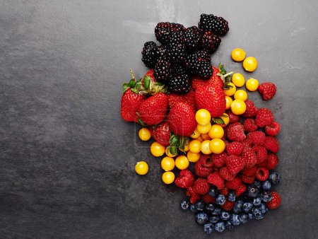 Photo for Theyre berry good for you. Studio shot of an assortment of berries lying on a dark countertop - Royalty Free Image