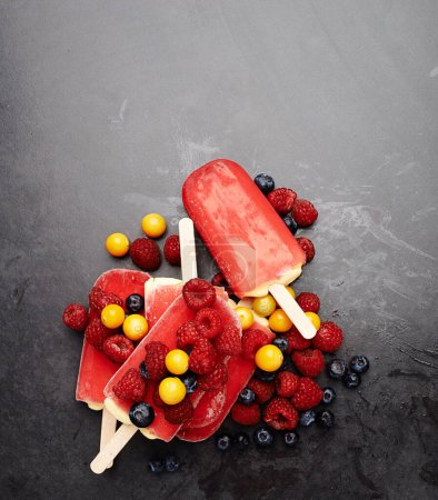 Photo for Mmm... fruity summer delights. Studio shot of berry ice lollies surrounded by an assortment of berries - Royalty Free Image