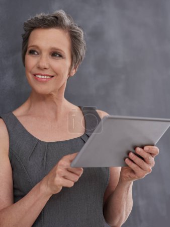 Photo for Work smarter, not harder. A mature businesswoman looking thoughtful while holding her digital tablet - Royalty Free Image