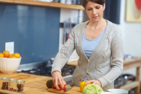Téléchargez les photos : Préparer un repas sain pour sa famille. une femme séduisante préparant la nourriture dans la cuisine - en image libre de droit