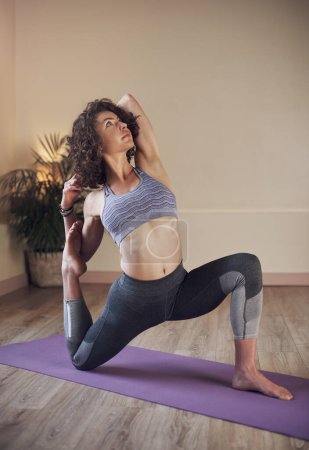 Foto de El yoga es realmente el arte de despertar. Foto completa de una atractiva joven que sostiene una pose de sirenas durante una sesión de yoga en interiores sola - Imagen libre de derechos