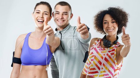 Photo for Youre only one workout away from a good mood. Three friends showing thumbs up while wearing sports clothing - Royalty Free Image