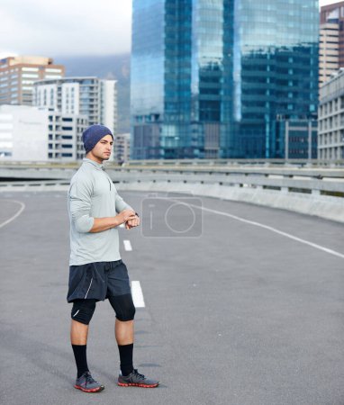 Foto de El mejor momento hasta ahora. un joven corredor comprobando el tiempo mientras está fuera para una carrera en la ciudad - Imagen libre de derechos