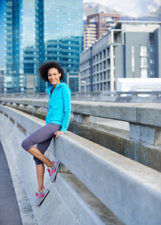 Téléchargez les photos : Je m'absente rapidement d'une course. Portrait d'une jeune joggeuse adossée à une balustrade dans la ville - en image libre de droit