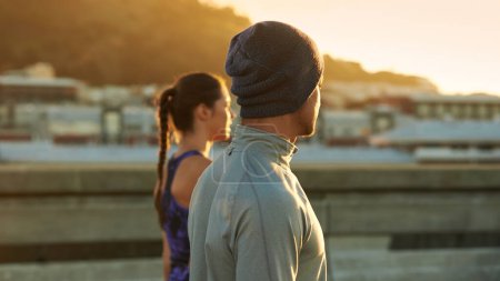 Téléchargez les photos : Course paisible du matin. deux jeunes joggeurs debout et regardant le lever du soleil - en image libre de droit