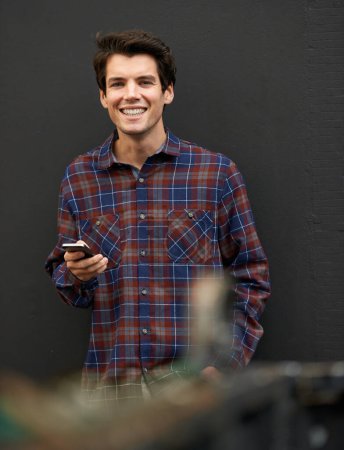 Foto de Technolgy tiene el mejor efecto en su humor. un joven guapo parado al aire libre usando un teléfono celular - Imagen libre de derechos