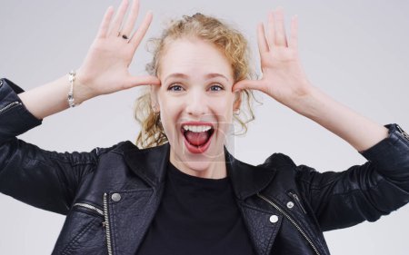 Photo for Rock out with your fun out. Studio shot of a young woman making a funny face against a gray background - Royalty Free Image