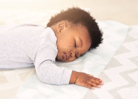 Foto de Bebé, niño africano y dormir en la cama para el descanso, la salud y la paz para el crecimiento, el desarrollo y relajarse en el hogar familiar. Niño negro, cansado y dormido en el dormitorio con fatiga, tranquilo y tranquilo en casa. - Imagen libre de derechos