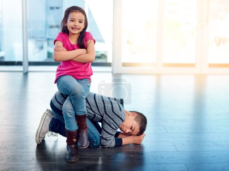 Photo for She always gets her way. an adorable little girl posing with her arms folded while sitting on her brothers back at home - Royalty Free Image