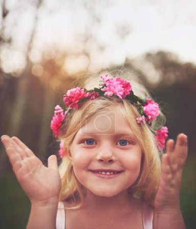 Foto de Echa un vistazo. una niña feliz sonriendo y mirando a la cámara después de abrir los ojos jugando a las escondidas en la naturaleza - Imagen libre de derechos