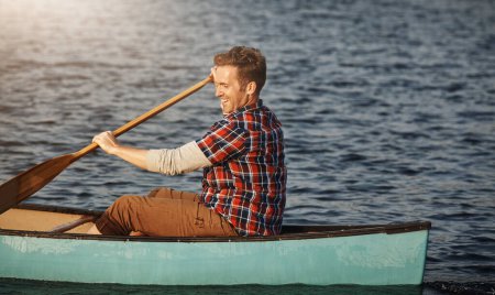 Téléchargez les photos : Le plus heureux du lac. un jeune homme ramant un bateau sur le lac - en image libre de droit