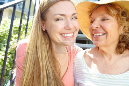 Téléchargez les photos : Passer du temps avec maman au soleil d'été. Une belle femme mûre souriant largement tout en accélérant le temps avec sa mère aînée - en image libre de droit