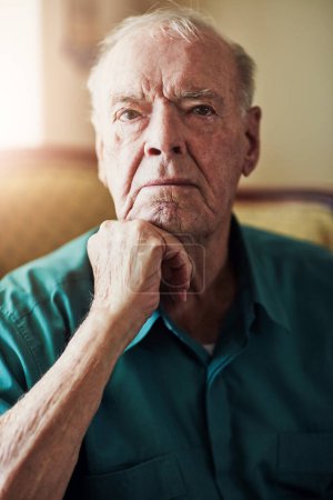 Foto de El silencio es el lenguaje de los sabios. Retrato recortado de un hombre mayor sentado con la mano en la barbilla en una sala de estar - Imagen libre de derechos
