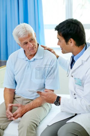 Photo for Consultation, doctor and old man in hospital room with advice, help and support from senior care clinic. Retirement, discussion on results and elderly patient sitting on bed with medical professional. - Royalty Free Image