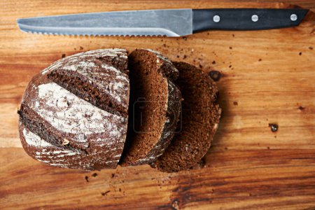 Téléchargez les photos : Bon et sain. Gros plan d'un pain coupé avec un couteau à côté - en image libre de droit