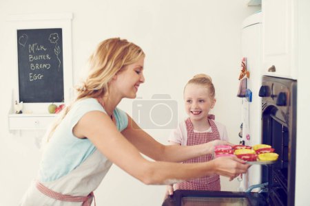 Foto de En el horno ahora... linda niña horneando en la cocina en casa con su mamá - Imagen libre de derechos