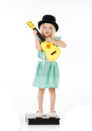 Foto de Es una mini músico. Estudio disparo de una linda niña jugando con su guitarra de juguete sobre un fondo blanco - Imagen libre de derechos