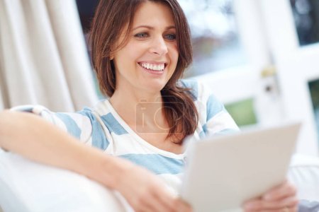 Photo for Theres so much to see on the net. a beautiful woman using a digital tablet while relaxing on the sofa at home - Royalty Free Image