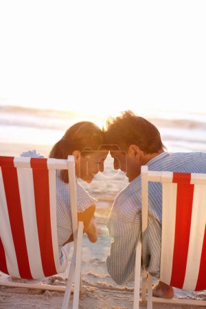 Foto de Haces todo perfecto. Una pareja cariñosa sentada en la playa al atardecer - Imagen libre de derechos