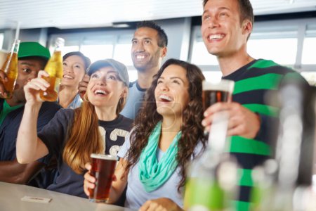 Photo for Watching an exciting game at the pub. A group of friends cheering on their favourite sports team at the bar - Royalty Free Image