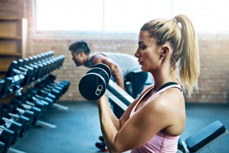 Photo for Being weak is a choice, so is being strong. a young woman doing weight exercises at the gym - Royalty Free Image
