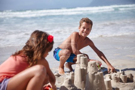 Téléchargez les photos : Construire des châteaux de sable impressionnants avec sis. un frère et une sœur heureux construisant des châteaux de sable ensemble à la plage - en image libre de droit